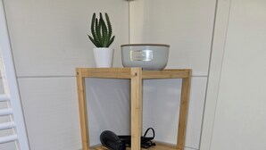 A wooden shelf unit with a potted plant and a bowl on top, holding a hairdryer and a towel. - WohnTraum zur alten Post, old town, sauna (Meißen)