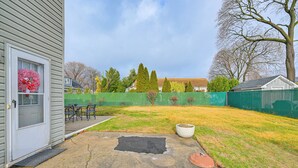 A backyard with a concrete patio, a small garden, and a green fence. - 2 Mi to UBS Arena: Wfh-friendly Couple's Retreat (Floral Park)