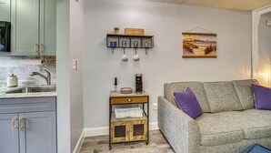 A kitchen with grey cabinets, a coffee machine, and a shelf with kitchenware. - Half-mi to Ocean: Cape Canaveral Beach Hideaway! (Cape Canaveral)