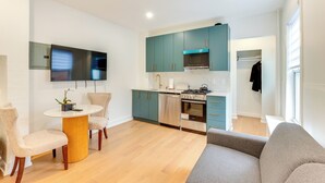 A modern kitchen with teal cabinets, a built-in oven, and a dining area with a round table and two chairs. - Centrally Located & Pet Friendly: Yonkers Studio! (Yonkers)