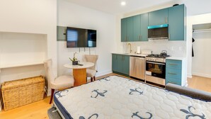 A compact kitchen with teal cabinets, a built-in oven, and a small dining area with a round table and chairs. - Centrally Located & Pet Friendly: Yonkers Studio! (Yonkers)