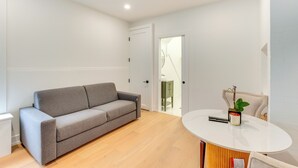 A modern living room with a grey sofa, a round white table, and a green cabinet. - Centrally Located & Pet Friendly: Yonkers Studio! (Yonkers)