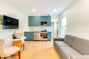 A modern kitchen with teal cabinets, a built-in oven, and a flat-screen TV mounted above the counter. - Centrally Located & Pet Friendly: Yonkers Studio! (Yonkers)