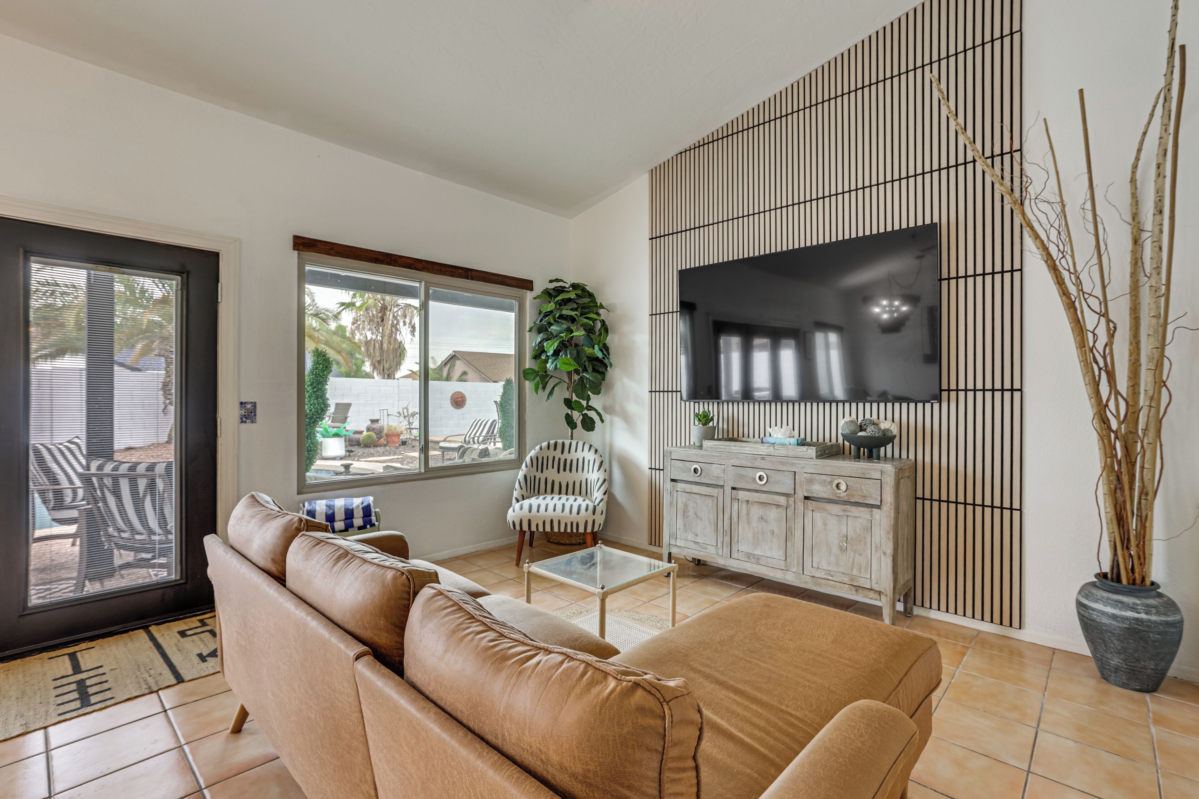 Una sala de estar con sofá, televisión, aparador y planta en maceta.