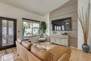 A living room with a sofa, a television, a cabinet, and a potted plant. - Seasonally Heated Pool: Phoenix Family Home! (Phoenix)