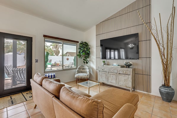 A living room with a sofa, a television, a cabinet, and a potted plant. - Seasonally Heated Pool: Phoenix Family Home! (Phoenix)