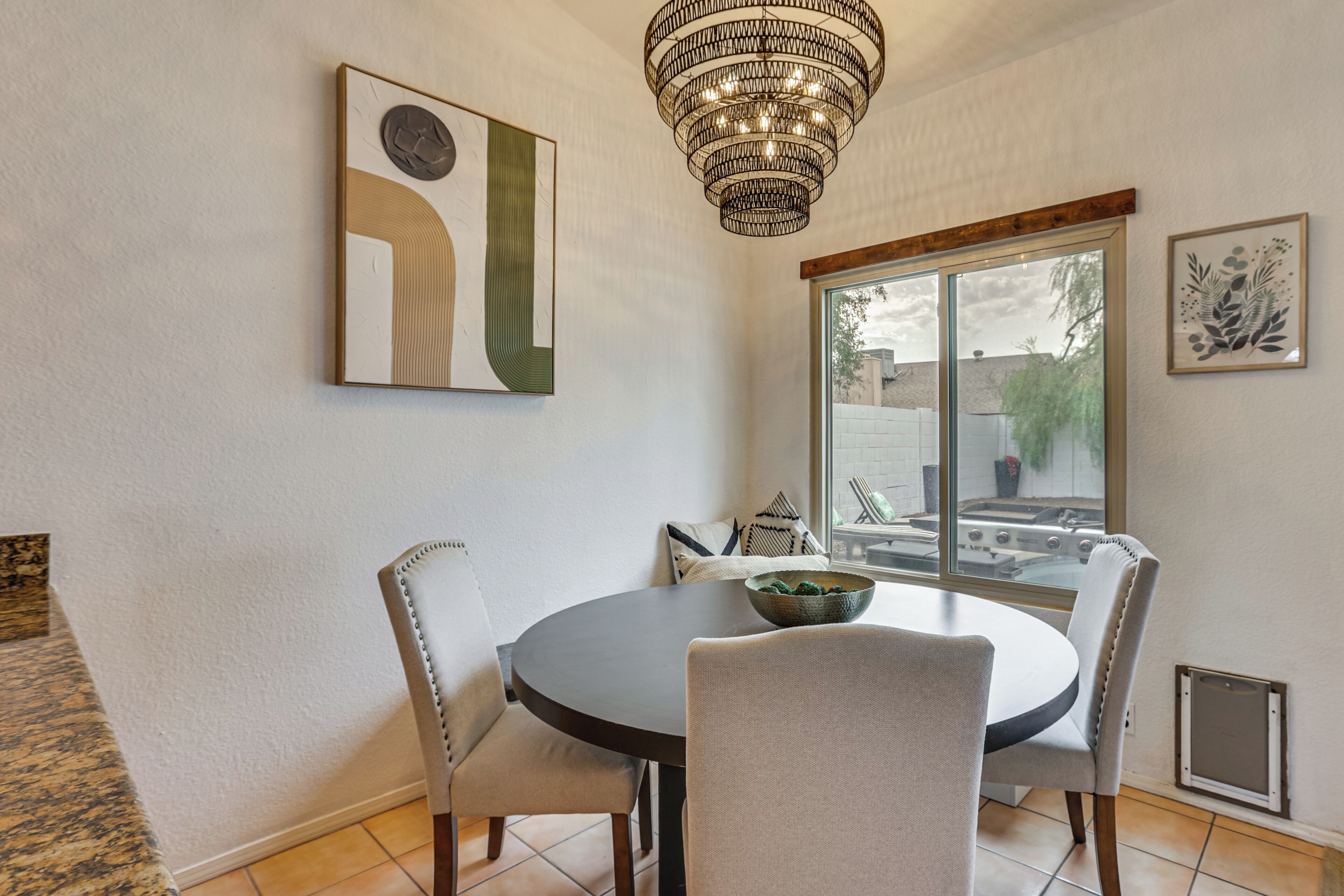 Un coin repas avec une table ronde, quatre chaises, un lustre et des œuvres d’art accrochées aux murs.
