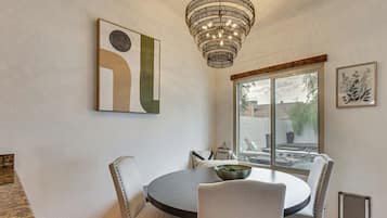 Un coin repas avec une table ronde, quatre chaises, un lustre et des œuvres d’art accrochées aux murs.
