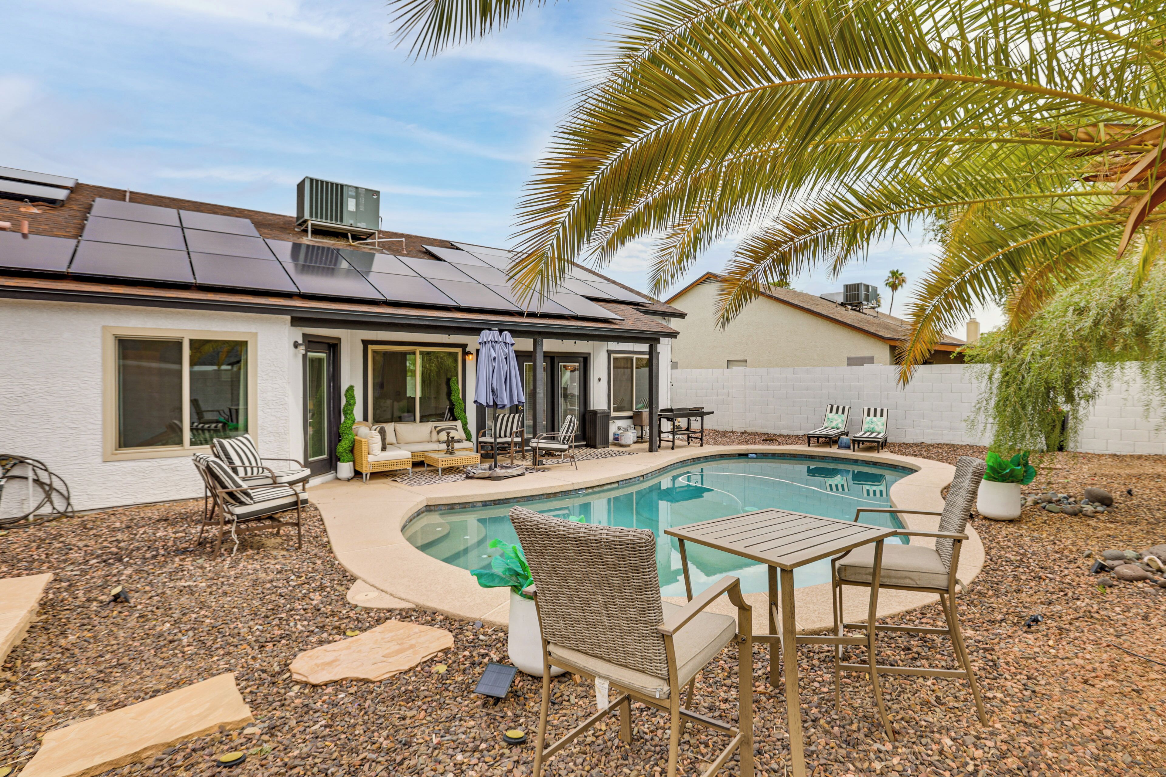 Une propriété résidentielle dotée d’une piscine, de mobilier d’extérieur et de panneaux solaires installés sur le toit.
