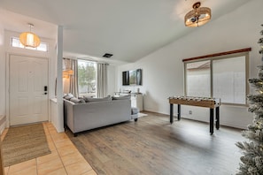 A modern living room with a grey sofa, a foosball table, and a television on the wall. - Seasonally Heated Pool: Phoenix Family Home! (Phoenix)