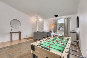 Ett modernt vardagsrum med ett fotbollsspel, en soffa, ett soffbord och en tv som är monterad på väggen.