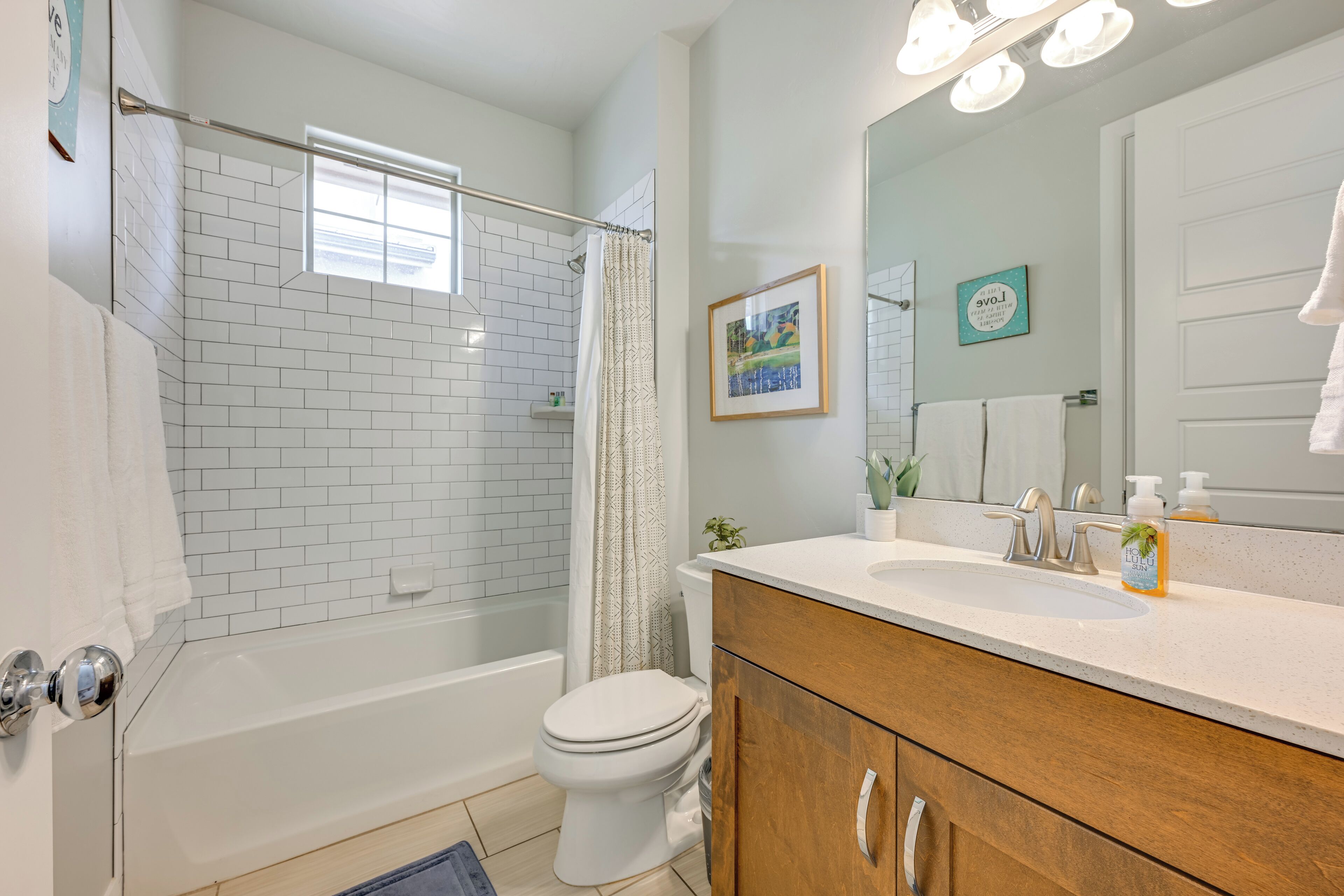 A bathroom with a bathtub, toilet, and vanity with a mirror.