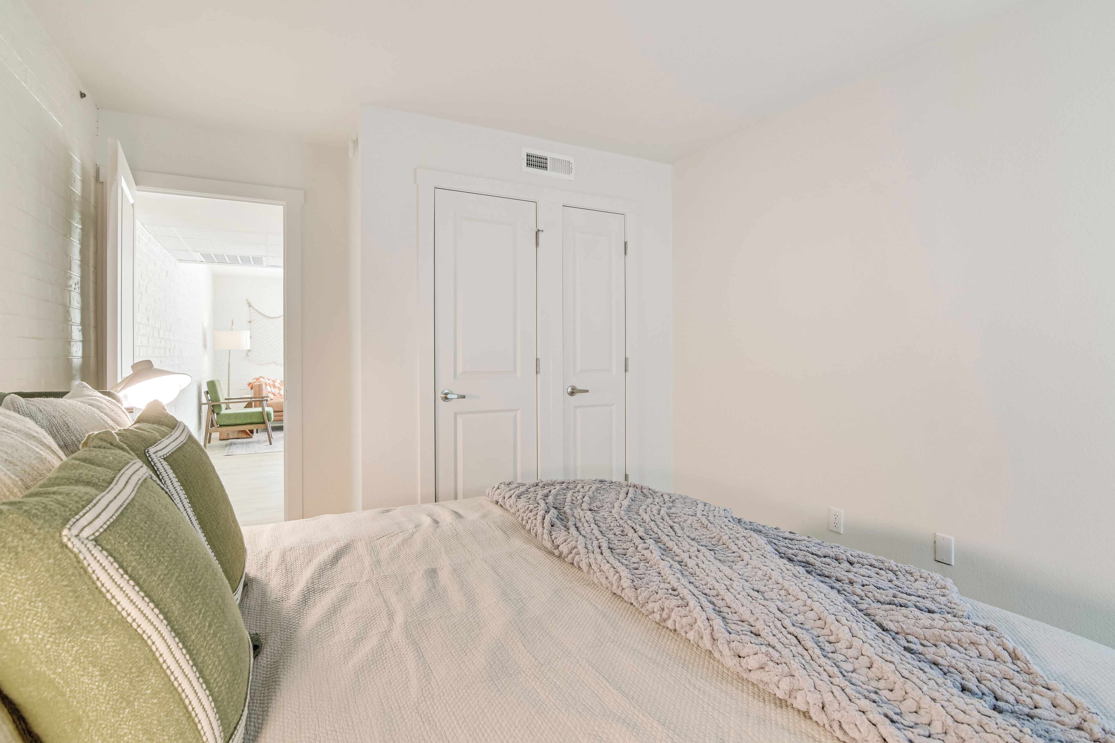 Een slaapkamer met een bed, een deur en uitzicht op een andere kamer.