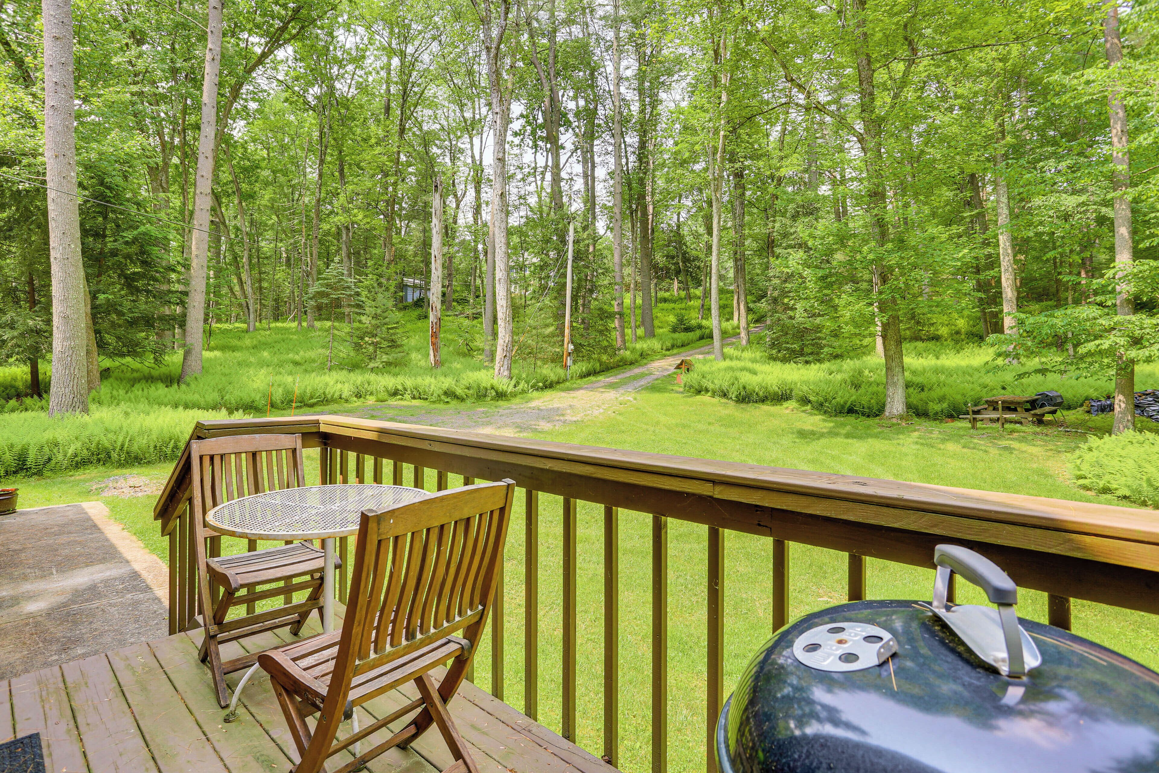A wooden deck with a table and chairs overlooking a forested area.