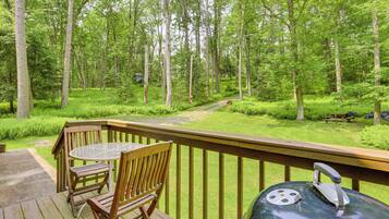 A wooden deck with a table and chairs overlooking a forested area.