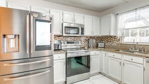 A modern kitchen with stainless steel appliances, white cabinetry, and a tiled backsplash. - 3 Mi to Marina: Riverview Family Home w/ Lanai! (Riverview)
