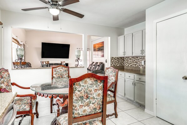A dining area with a round glass table, floral upholstered chairs, a ceiling fan, and a flat-screen TV mounted on the wall. - 3 Mi to Marina: Riverview Family Home w/ Lanai! (Riverview)