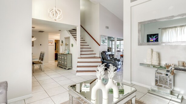 A spacious living area with a glass coffee table, a staircase, and a modern chandelier. - 3 Mi to Marina: Riverview Family Home w/ Lanai! (Riverview)