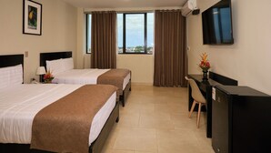 Une chambre d’hôtel avec deux lits, un bureau, une télévision et une fenêtre avec des rideaux.