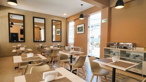 Un espace repas moderne, doté de tables et de chaises, de grands miroirs et d’un buffet.