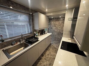 Una cucina moderna con lavello in acciaio inossidabile, forno integrato e pannello di schienale in marmo.