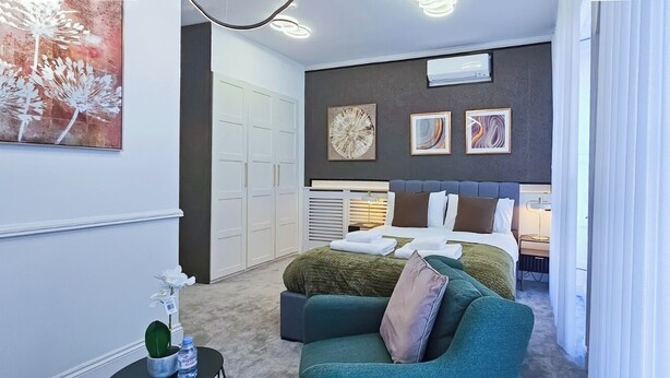 A modern bedroom with a bed, a sofa, and a wardrobe.