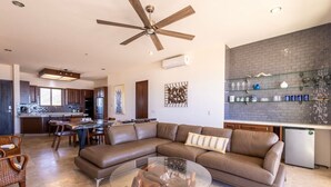 Uma sala de estar moderna com sofá seccional, mesa de centro de vidro e área de jantar com cadeiras.