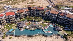 Um resort com vários edifícios, piscina central e área de praia.