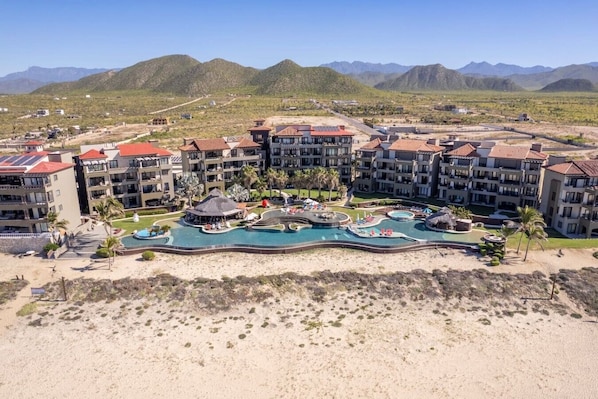 A resort with multiple buildings, a central pool area, and a mountainous backdrop.