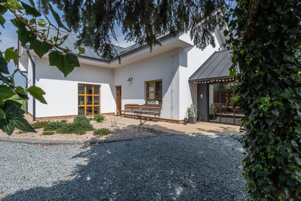 A modern house with a gravel driveway, a wooden bench, and a small garden area.