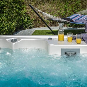 A hot tub with a hammock and two glasses of orange juice.