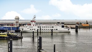 A ferry docked at a pier with a clear view of the water and distant shoreline.