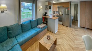 A compact living space with a sofa, a small coffee table, a kitchenette, and a view of the outdoors.