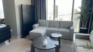 A modern living room with a grey sectional sofa, a round coffee table, and a black TV stand.