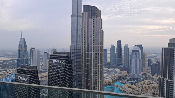 A high-rise building with the name "EMAAR" on its facade, surrounded by other tall buildings in a cityscape.