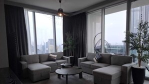 A modern living room with a sectional sofa, a coffee table, and large windows offering a city view.