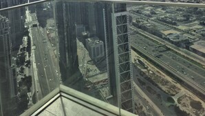 A high-rise building with a view of a cityscape, including various skyscrapers and a highway.