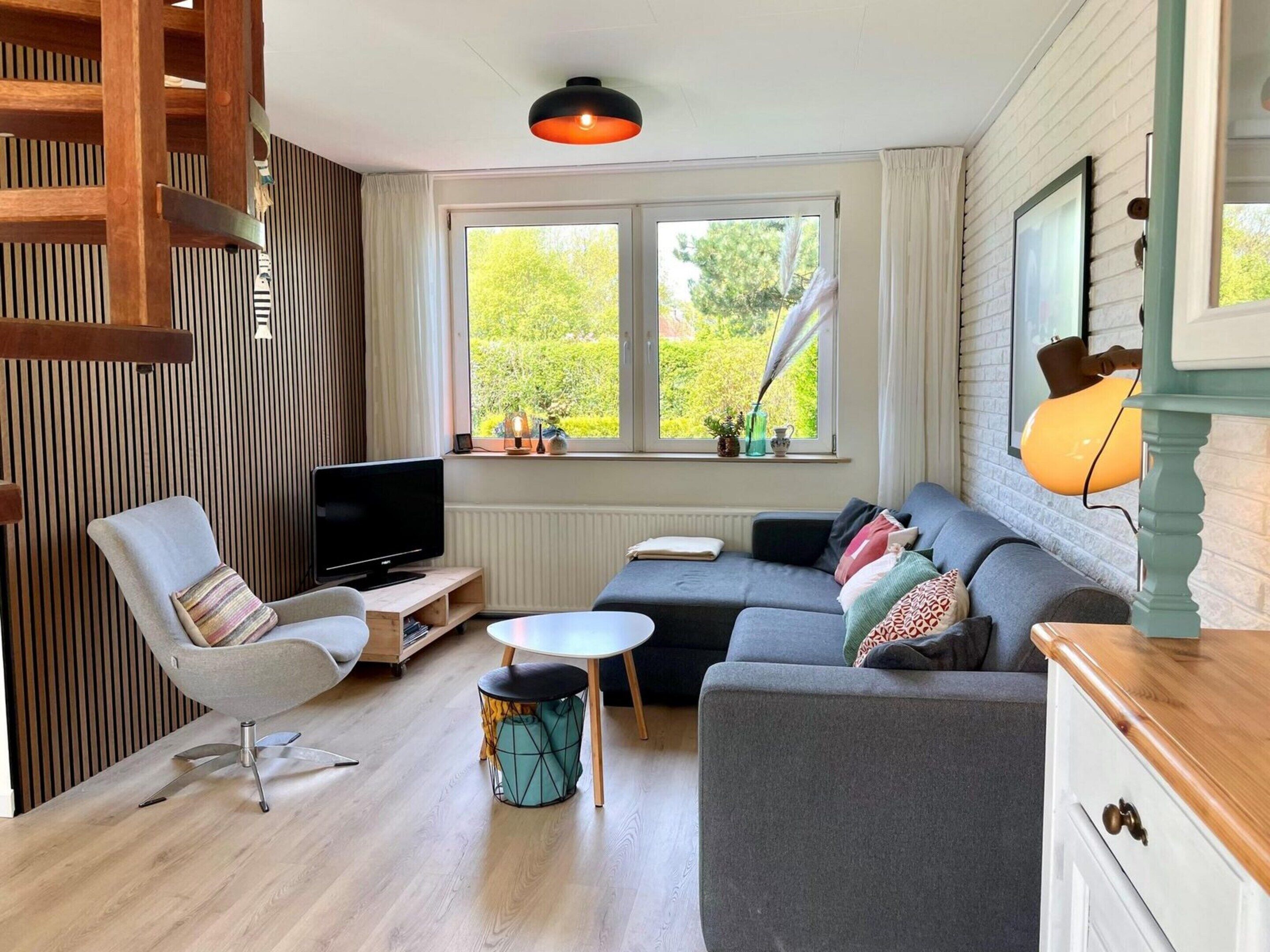 A modern living room with a TV, sofa, and a small round table.