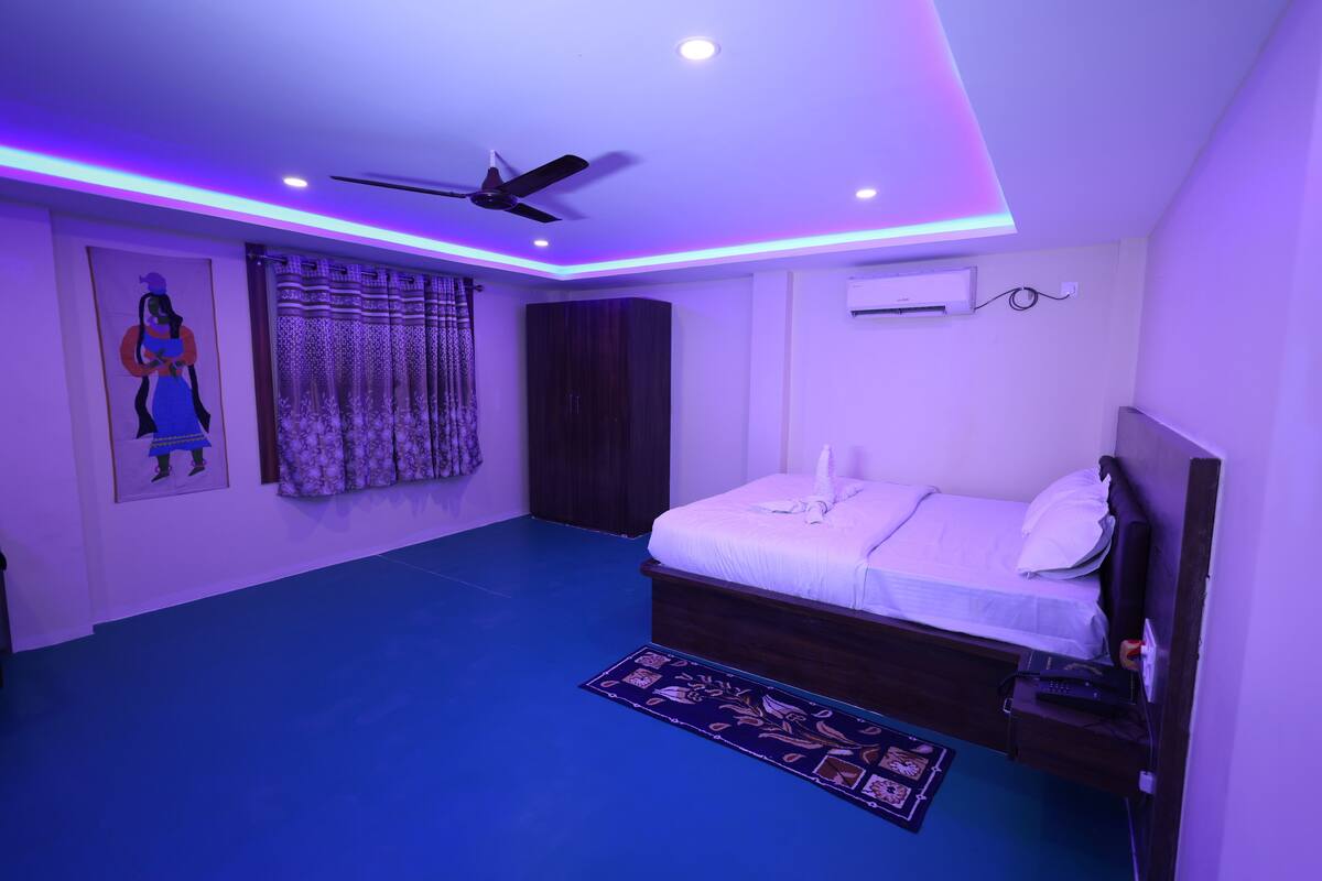 A bedroom with a bed, a ceiling fan, an air conditioning unit, and a patterned rug.