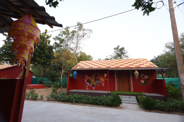 A small building with a checkered roof, a mural on the wall, and a small porch. - SHRIMAN VALLEY (Gop)