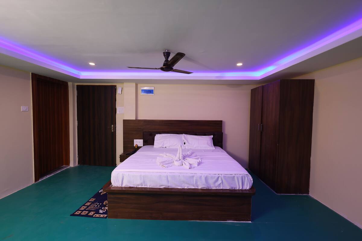A bedroom with a bed, a ceiling fan, and a wooden wardrobe.