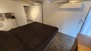 A small, compact room with a single bed, a built-in bench, and a wall-mounted air conditioner. - 1BR Mountain View #2 - 1000mbps WiFi (Ko Pha-ngan)