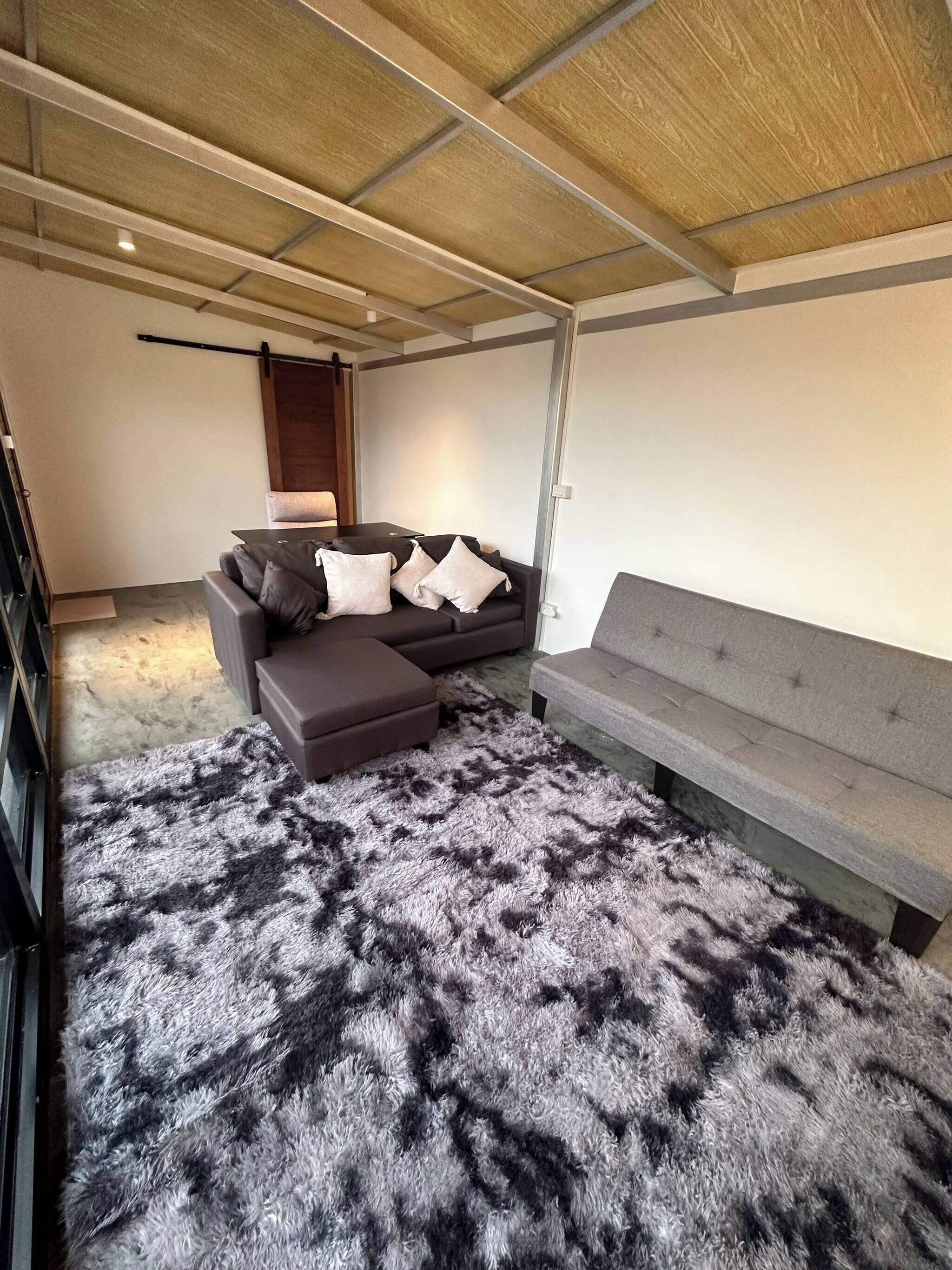A modern living room with a grey sofa, a grey bench, and a fluffy rug.