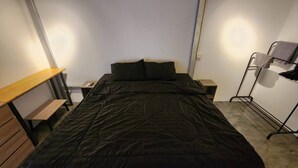 A small, compact bedroom with a single bed, a wooden bench, and a metal rack with clothes. - 1BR Mountain View #2 - 1000mbps WiFi (Ko Pha-ngan)