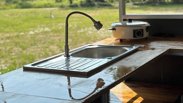 A kitchen with a sink, a portable stove, and a view of a green landscape. - 1BR Mountain View #2 - 1000mbps WiFi (Ko Pha-ngan)