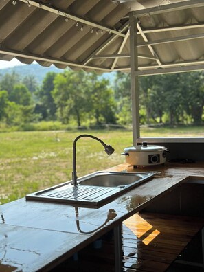 A kitchen with a sink, a portable stove, and a view of a green landscape. - 1BR Mountain View #2 - 1000mbps WiFi (Ko Pha-ngan)