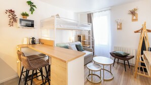 A compact, well-lit room with a bunk bed, a small kitchen area, a dining table, and a cozy seating arrangement. - Stylish & fully equipped apt. only 5 min to metro. Nice area near the Bastille.  (Paris)