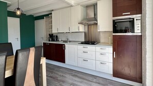 A compact kitchen with white and dark brown cabinets, a stainless steel range hood, and a built-in microwave. - Appealing Holiday Home for Family (Sint Maartensvlotbrug)