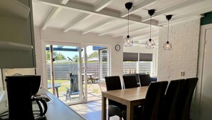 A modern kitchen with a coffee maker, a dining table with chairs, and a view of the backyard through a glass door. - Appealing Holiday Home for Family (Sint Maartensvlotbrug)