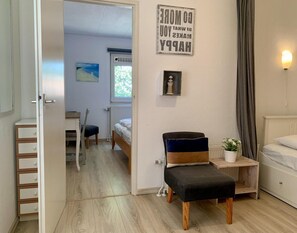 A bedroom with a bed, a chair, a small table with a plant, and a sign on the wall. - Sunny Garden Retreat Bungalow (Sint Maartensvlotbrug)